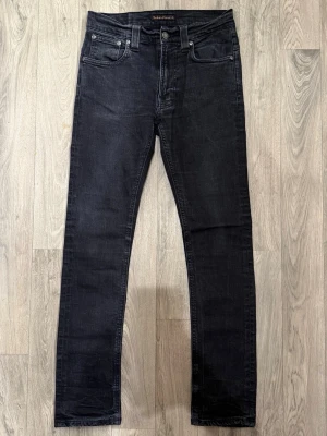 Nudie Jeans Svart W31/L32 - Slim Fit - Mycket fint skick. Mått - Midja: 36cm, Ytterbenslängd: 100,5cm, Benöppning: 15,5cm. Modellen är 185cm & 63kg. Hör av dig vid funderingar!🤝