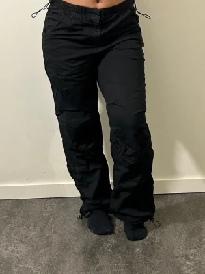 Svarta cargobyxor med dragsko - Säljer ett par svarta cargobyxor med avslappnad passform och dragsko i midjanja samt vid benslut. 
