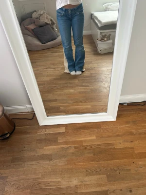 Blå bootcut jeans med dubbla knappar - Säljer ett par blå bootcut jeans med dubbla knappar i midjan och klassiska fickor fram och bak. Jeansen har en snygg tvätt och är i mjukt denimtyg. Jag har sytt om dom till bootcut jeans med ett beige jeanstyg. (W 83cm, innebenslängd 80cm). Skriv för frågor💕
