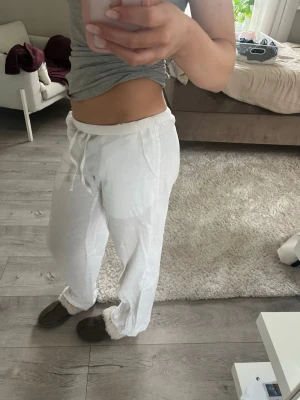 Vita linnebyxor med dragsko - Säljer ett par vita linnebyxor med avslappnad passform. Byxorna har raka ben och är tillverkade i ett tunt, luftigt linnematerial som passar perfekt för en chill och bekväm stil. Lappen är borttagen men skulle tippa på att de är i xs!