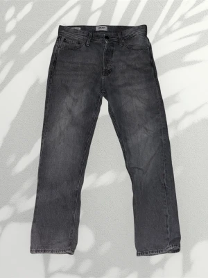Jack & jones jeans - Snygga grå jeans från jack & jones med rak passform och klassisk femficksdesign. Jeansen har en diskret tvättad look och är tillverkade i bomull. Perfekta för en avslappnad och trendig stil. Modell: relaxed chris. Storlek 28/30.