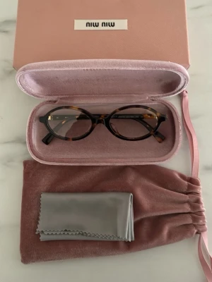 Miu miu glasögon - Upptäck säsongens måste-ha: virala Miu Miu-glasögon som kombinerar trend och funktion i perfekt balans. Inspirerade av de ikoniska modellerna från Miu Miu ger de dig en exklusiv, fashion-forward look – oavsett om du stylar dem till vardags eller bär dem framför skärmen. Med inbyggt blåljusfilter skyddar de dina ögon vid dator- och mobilanvändning, samtidigt som de lyfter hela din outfit. Perfekta för jobbet, plugget eller cityrundan – ett statement-plagg som faktiskt gör skillnad