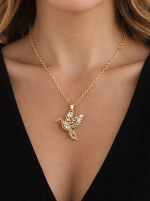 Guldigt halsband med fågelhänge - Unikt halsband i guldfärgad metall med ett detaljerat hänge i form av en fågel. Hänget är dekorerat med färgglada stenar och gnistrande pärlor som ger en exklusiv känsla. Kedjan är tunn och elegant, perfekt för att lyfta vilken outfit som helst.