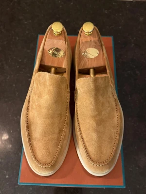 Loro piana summer walk  - Snygga loafers i beige mocka med stilren design och vit sula. Skorna har klassisk form och diskreta sömmar runt tån. Perfekta för en avslappnad men ändå uppklädd look.