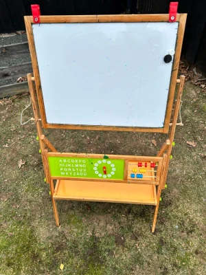 Stående lektavla med griffeltavla och whiteboard - Säljer en stående lektavla i trä med både griffeltavla och whiteboard. Tavlan har en grön sektion med alfabetet, en klocka för att öva tid samt kulram med färgglada kulor. Under finns en praktisk hylla för förvaring av tillbehör.