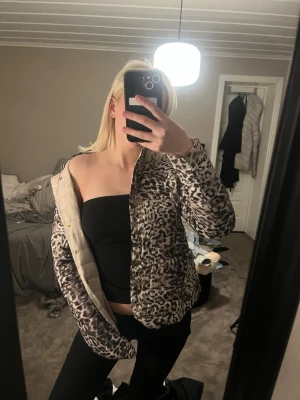 Leopardmönstrad pufferjacka - Snygg leopardmönstrad pufferjacka med hög krage och knappar framtill. Jackan har en beige insida och är perfekt för dig som vill sticka ut med ett djurmönster. Passar till både chill och trendiga outfits.