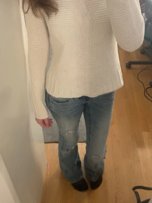 Vit stickad tröja med stjärnmönster - Säljer en vit stickad tröja med ett snyggt stjärnmönster framtill. Tröjan har rund halsringning, långa ärmar och ribbade muddar vid ärmslut och nederkant. Perfekt för dig som gillar enkel men cool stil.