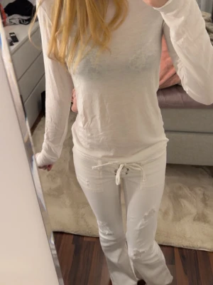Vit långärmad topp - Säljer en enkel och stilren vit långärmad topp. Toppen har en klassisk passform och är perfekt att styla med jeans eller kjol. Den är tunn och lätt, vilket gör den skön att bära under varmare dagar eller som lager.💕 storlek M men skulle säga att den passar som S