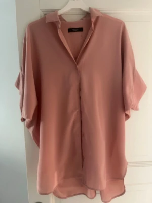 Rosa skjorta från Max Mara Weekend - Säljer en oversized rosa skjorta från Max Mara Weekend. Skjortan har klassisk krage, knappar framtill och korta ärmar. Materialet känns lätt och flowy, perfekt för en chill och stilren look. Skjortan är oversized
