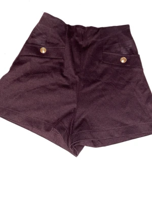 Mörkbruna högmidjade shorts - Snygga mörkbruna högmidjade shorts med två framfickor och dekorativa guldknappar. Klassisk och stilren design med korta ben och mjukt material som ger en bekväm passform.
