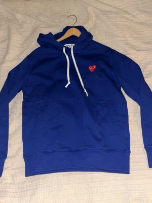 Blå hoodie Comme des Garçons Play - En stilren blå cdg hoodie, som passar alla stilar. Sitter bra i passformen och är väldigt originell och snygg, hör av vid minsta intresse!