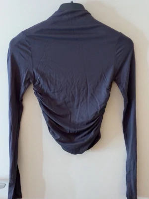 Tröja Gina tricot  - Blågrå tröja från Gina tricot som är tight i midjan, halvt polo och slits längst ner på armarna. Oanvänd med lapp kvar