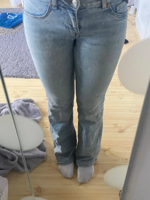 Ljusblå bootcut jeans - Säljer ett par ljusblå bootcut jeans med klassisk femficksdesign och hög midja. Jeansen har en snygg tvättad look och raka ben som går ut lite nedtill. Perfekta till sneakers eller boots och passar till många olika stilar.