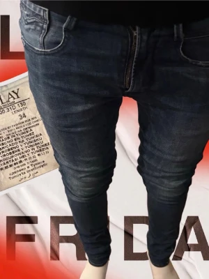 Mörkblå slim fit jeans från Replay - Säljer ett par mörkblå slim fit jeans från Replay med snygga slitningar och tvättade detaljer. Jeansen har klassisk femficksdesign, dragkedjegylf och smal passform som sitter tight hela vägen ner. Perfekta för en trendig och avslappnad look.