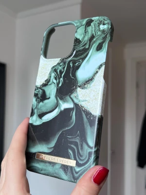 Grönt marmorerat mobilskal iDeal of Sweden (iPhone 13 Pro Max) - Snyggt mobilskal från iDeal of Sweden med grönt marmorerat mönster och inslag av guldglitter. Gjort i hårdplast och den klassiska loggan nedtill. (iPhone 13 Pro Max)