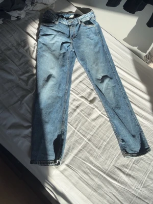 Ljusblå raka jeans - Säljer ett par ljusblå jeans med rak passform och klassisk femficksdesign. Jeansen har normal midja och är tillverkade i denim. Perfekta för en avslappnad och trendig stil.