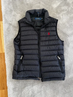 Svart dunväst från Polo Ralph Lauren - Snygg svart dunväst från Polo Ralph Lauren och perfekt för de varmare tiderna som börjar komma.