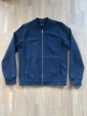 Marin blå Overshirt från Bondelid  - En väldigt stilig marinblå Overshirt från Bondelid. Ny skick! Endast använd ett fåtal gånger. Perfekt nu till våren och hösten! Måtten: Länd 64cm, Bredd 42cm S/M. Hör gärna av dig vid frågor eller funderingar!