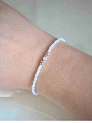 Handgjort armband – Vitt med rosa pärla🌸 - Handgjort armband med vita pärlor, silvriga detaljer och en rosa pärla i mitten  Ett elegant och minimalistiskt smycke som passar perfekt till vardag och att ge bort i present  Armbandet är elastiskt och varje exemplar är unikt då det är gjort för hand.  ✨ Detaljer , - Handgjort - Färg: vit, rosa och silvriga detaljer  - Material: Seed Beads - Storlek: Ca 17 cm - Typ: elastiskt  💌 Kolla gärna mina andra smycken