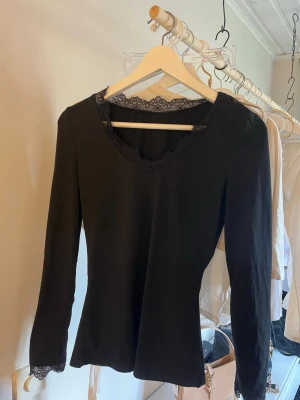 Svart långärmad topp med spets - Svart långärmad topp med v-ringning och fina spetsdetaljer vid halsringning och ärmslut. Snygg och enkel modell som passar till mycket🥰🥰