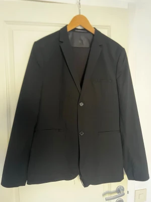  kostym med kavaj och byxor -  svart klassisk kostym med enkelknäppt kavaj och matchande byxor. Tveka inte på att höra av dig.