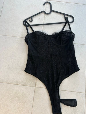 Svart spetskorsett med tunna band - Snygg svart korsett med spetsdetaljer och tunna axelband. Passar lika bra till kjol som till jeans och kavaj. Den är helt ny då den va lite för liten för mig. ( Passar nog om man har storlek M/L