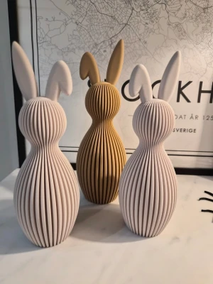 Dekorativa kaniner i modern design - Tre stilrena dekorationsfigurer formade som kaniner i beige och ljusbrun färg. Kaninerna har räfflad yta och långsmala öron, tillverkade i ett matt material som ger en modern och minimalistisk känsla. Perfekta som inredningsdetaljer i hemmet. Största kaninen är 21.5cm hög (den beiga) de två vita är ca 19cm. Jag skickar snabbt!