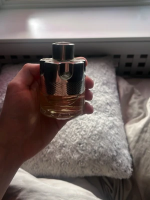 Azzaro Wanted Eau de Toilette - Säljer en Azzaro Wanted Eau de Toilette med en unik flaska som liknar en revolvertrumma. Flaskan är i glas med silverfärgat metallock och detaljer. Doften är maskulin och modern, perfekt för dig som vill sticka ut med en cool design på parfymhyllan. 40 ml kvar i flaskan!