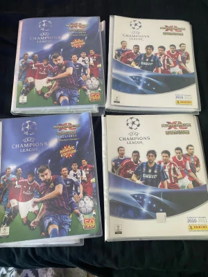 Panini Champions League samlaralbum - Fyra samlaralbum från Panini Adrenalyn Champions League, med plastfickor fyllda av fotbollskort från säsongerna 2010-2012. Omslagen är färgglada med fotbollsspelare och UEFA-logga. Perfekt för dig som gillar fotboll och samlarkort.