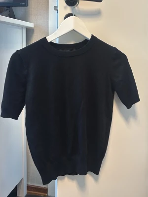 Svart stickad topp med kort ärm - Samma som förra men mer skönare material. Vanlig kort ärmad t shirt som sitter lite tjat vid midjan. Jätte skön t shirt