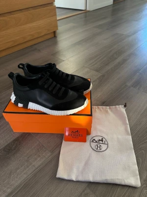 H skor svart - Snygga svarta H sneakers med chunky vit sula coola detaljer på sidan. Skorna har en mix av läder och textil, elastiska snören och en modern, sportig look. Kommer med original orange box och dustbag.