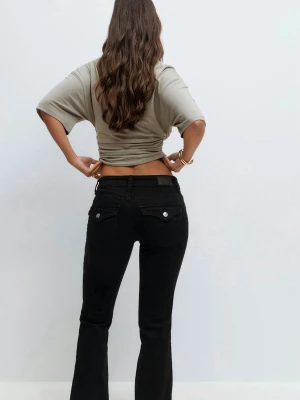 Svarta bootcut jeans från Gina tricot  - Snygga svarta bootcut jeans från Gina tricot med klassiska  fickor och silverfärgade knappar på bakfickorna. Jeansen har en något utsvängd passform och är tillverkade i ett mjukt denimtyg som sitter bekvämt. Perfekta för en trendig och avslappnad look. Aldrig använda för att jag inte gillade att de va tighta