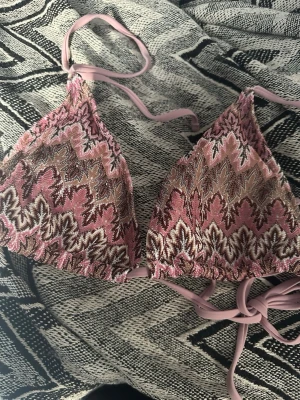 Rosa mönstrad trekantsbikini med knytning vid ryggen  - Säljer en snygg trekantsbikini i rosa med broderat bladmönster i brunt, vitt och beige. Bikinin har tunna knytband i matchande rosa och är fodrad på insidan.  Bikinin är i toppskick och oanvänd💗