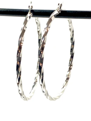 Silvriga tvistade creoler örhängen - Säljer ett par stora, silvriga creoler med tvistad design. Örhängena har en blank, reflekterande yta som ger en modern och trendig look. Material är i rostfritt stål och är 5.5cm stora 