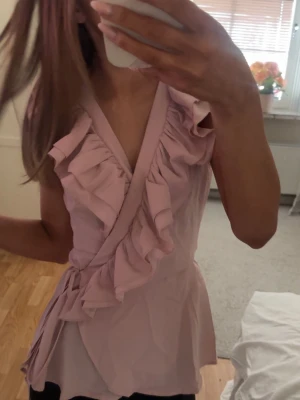 Ljusrosa omlottblus med volanger - Supersöt ljusrosa omlottblus med volangdetaljer💕köpt på vinted men jag har bara testat den💕såg när jag fick hem den att det var en fläck (sista bilden) men den är på insidan så den syns inte