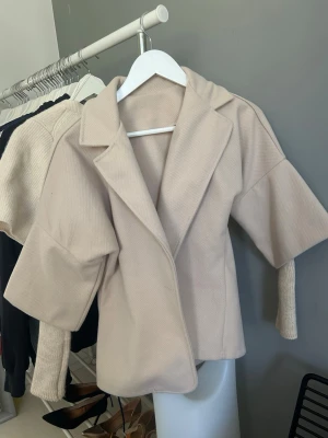 Beige kappa med stickade ärmar - Trendig beige cardiganjacka med bred krage och unika stickade muddar på ärmarna. Storlek xxs-s. Köpt på marknad i polen. Vet ej original märke.