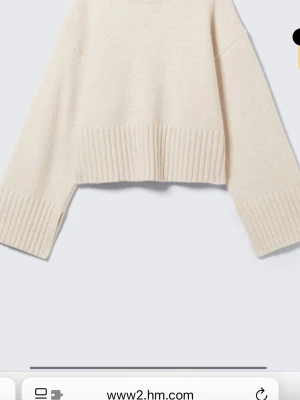 Beige croppad stickad tröja H&M - Trendig croppad stickad tröja i beige från H&M. Tröjan har breda ribbade muddar vid ärmslut och nederkant samt en avslappnad, boxig passform. Perfekt för lager på lager och enkel att styla till olika outfits.