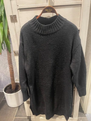 Oversized svart stickad tröja - Säljer en oversized svart stickad tröja med grov ribbad polokrage och muddar vid ärmslut och nederkant. Tröjan har en rak och avslappnad passform, perfekt för lager på lager. Materialet känns mjukt och värmande.