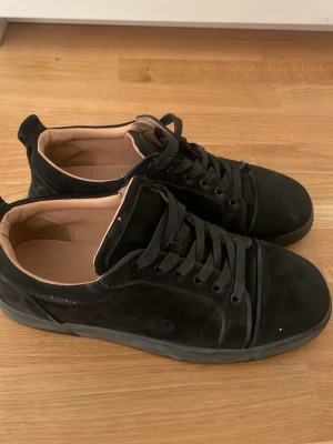 Svarta sneakers med röd sula - Stilrena svarta sneakers med ovandel i mocka och klassisk snörning. Skorna har en unik röd sula och beige innersida som ger en snygg kontrast. Perfekta för dig som gillar minimalistisk design med en twist. Kan gå ner i pris