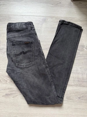 Svarta jeans från Nudie Jeans - Säljer ett par svarta jeans från Nudie Jeans i storlek W29 L34. Slim passform med snygg tvätt och skön, lätt sliten look.  Väldigt fint skick. Vid fundering är det bara att hojta till ! 