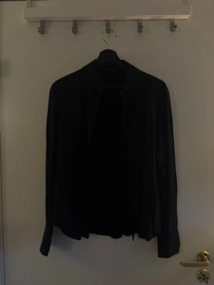 Svart långärmad skjorta - Stilren svart långärmad skjorta med klassisk krage och knäppning framtill. Skjortan har en rak passform och är tillverkad i ett mjukt, tunt tyg som ger en avslappnad look. Perfekt att matcha med jeans eller chinos.Hör av dig om du har några frågor! 💗🫶🏼