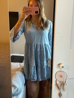 Ljusblå volangklänning med v-ringning - Söt ljusblå klänning med v-ringning och trekvartsärmar. Klänningen har volangdetaljer och är tillverkad i ett tunt, luftigt tyg som ger en avslappnad och flowy känsla. Perfekt för varma dagar och enkel att styla med smycken. Passar bra på mig som brukar ha M❣️