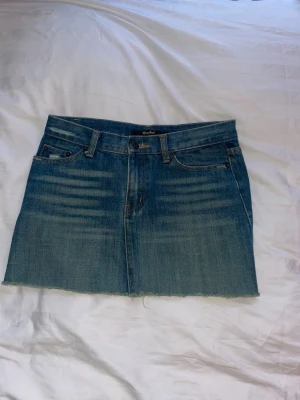 Populär jeanskjol - Säljer en blå jeanskjol från Crocker med klassisk femficksdesign och rå, avklippt kant nertill. Kjolen har bälteshällor och knappgylf framtill. Perfekt för dig som gillar en avslappnad och trendig denimlook.