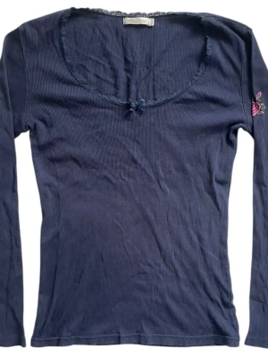 Långärmad tröja från Happy Holly - Mörkblå långärmad ribbad tröja med spets urringning, rosettdetalj och rostryck på ena armen 💙Jag brukar ha strl XS i toppar för referens!