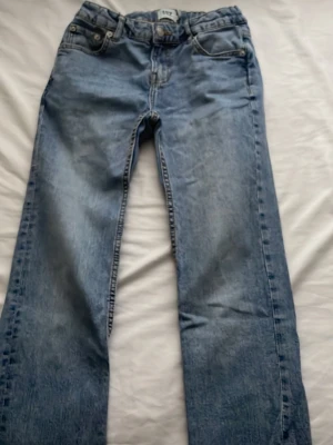 Ljusblå raka jeans från H&M - Säljer ett par ljusblå jeans från H&M med rak passform och klassisk femficksdesign. Jeansen har normal midja och är tillverkade i denim med snygg tvättad look. Perfekta för en avslappnad stil.