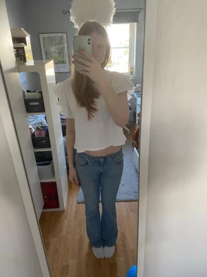 Vit croppad topp med volangärmar - Söt vit croppad topp med volangärmar och rund hals. Den är från Zara och är köpt för flera år sedan. Toppen har en lös passform och är tillverkad i ett mjukt bomullsliknande material. Perfekt för dig som gillar en enkel men trendig stil. Fråga vid eventuella frågor 💕