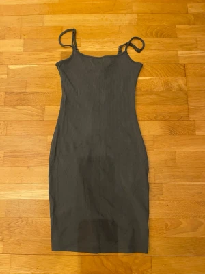 Militärgrön ribbad midiklänning - Säljer en militärgrön ribbad klänning stl.32 med smala axelband och kroppsnära passform. Klänningen är ärmlös och har en enkel, stilren design som passar perfekt till många olika tillfällen. Materialet är stretchigt och bekvämt.