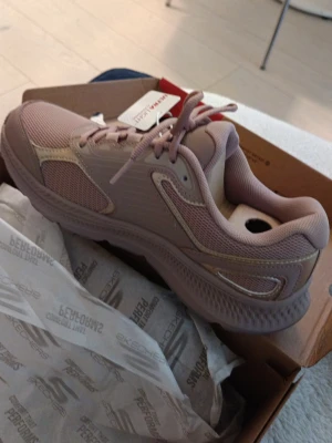 Beige sneakers från Skechers - Snygga beige sneakers från Skechers med mesh- och syntetdetaljer. Modellen har en chunky sula och klassisk snörning. Perfekt för dig som gillar sportig stil och vill ha bekväma skor till vardags. Märket syns på hälen och skon har en modern design.