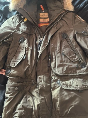 Olivgrön Parajumpers parkas med pälskant - Säljer en olivgrön Parajumpers Masterpiece Series Anthology i storlek Medium (Slim fit). Jackan är i princip som ny då den bara är använd ca 3–5 gånger totalt, så den är i toppskick utan slitage. Den är 100% ÄKTA! Priset kan diskuteras!