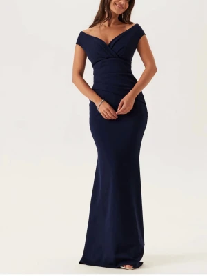 Marinblå Bal klänning - Helt ny, aldrig använd. Elegant marinblå långklänning med offshoulder-design och figurnära passform. Klänningen har en djup v-ringning och vackra draperade detaljer över bysten. Perfekt för bal eller festliga tillfällen. 